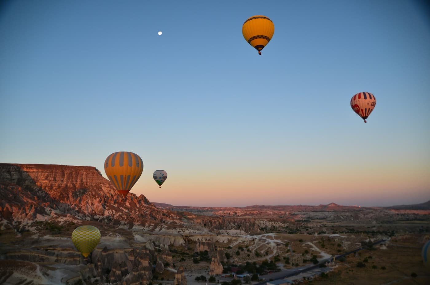 Half a dozen hot air balloons drifting over the Cappadocian valleys at dawn.