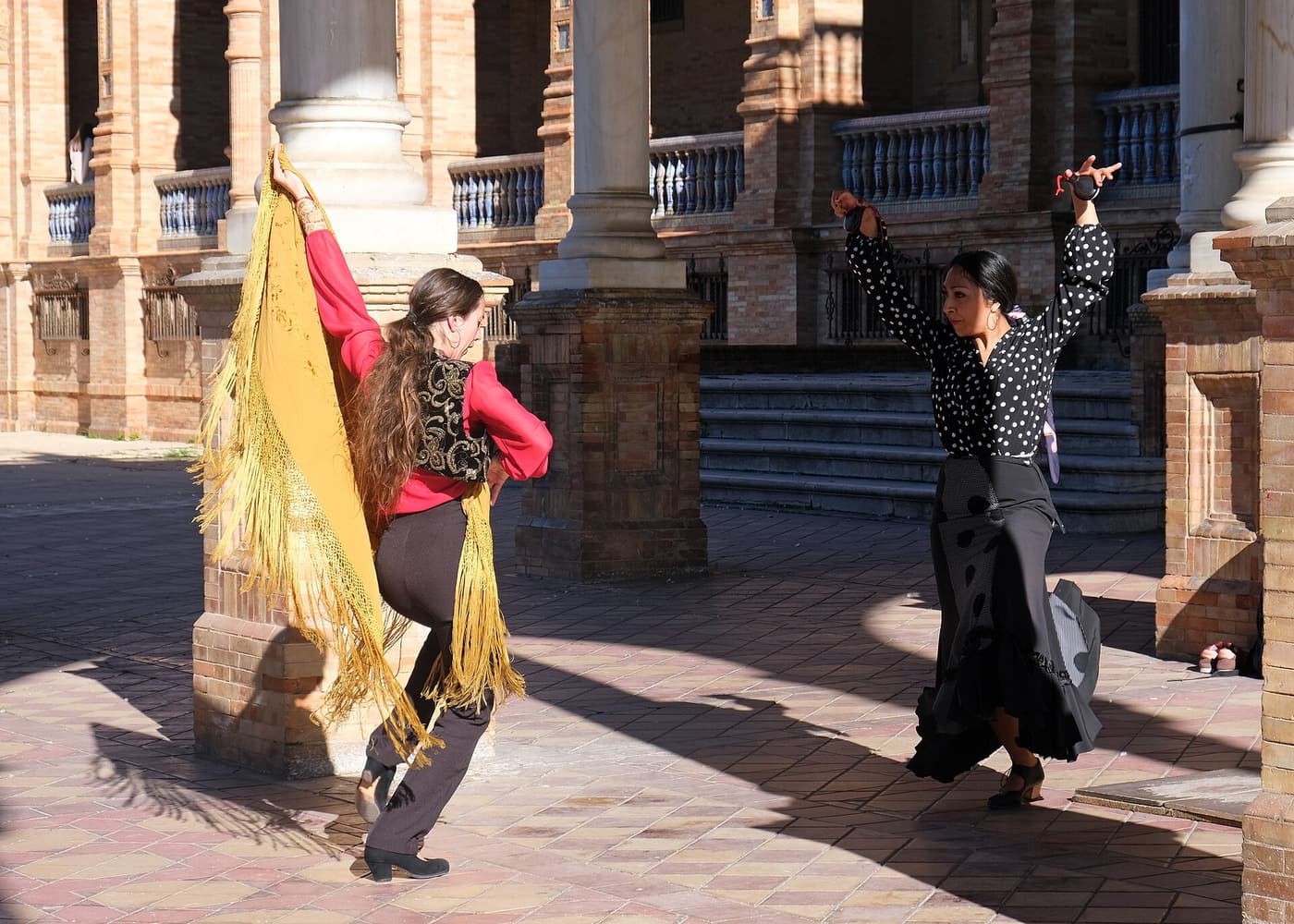 Two flamenco dancers performing in the arcade of the Plaza de España in Seville.