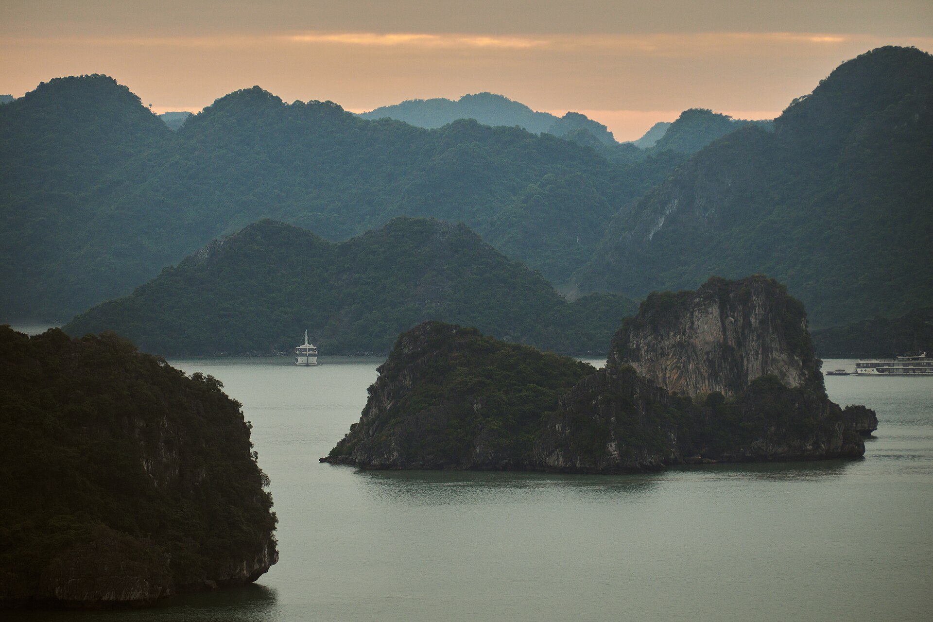 Limestone karst islands rising out of still water in Ha Long Bay.